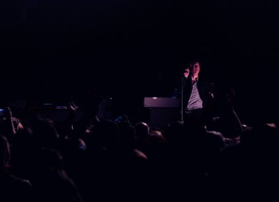 Spoon frontman Britt Daniel spotlit from the dark room and the sea of fans. Photo: Lmsorenson.net