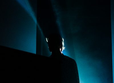 FINNEAS creeps on stage and stands in the fog, backlit by the lasers behind him.