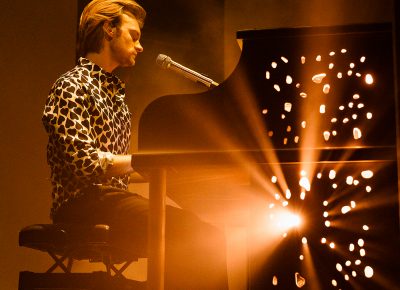 FINNEAS taking it slow while playing on the piano with Swiss cheese holes as the light spews out of it during his set.