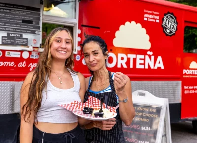 (L-R) Claire and Kelly share empanadas from Porteña’s food truck. ¡Buen provecho! Photo: John Barkiple.