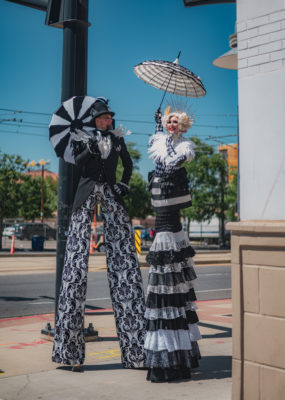 Heidi and Chad pose on stilts on the sidewalk.