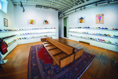 A room with hardwood floors surrounded by white shelves with shoes on display.