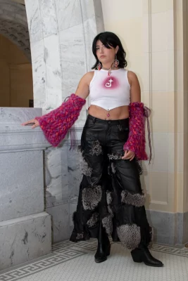 Ashley Favila poses in a white tank, fur-covered black leather pants and pink yarn arm warmers. 