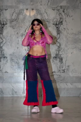 Ashley Favila wears purple jeans with blue yarn on the bottom, a punk lacey shrug and bold sunglasses.