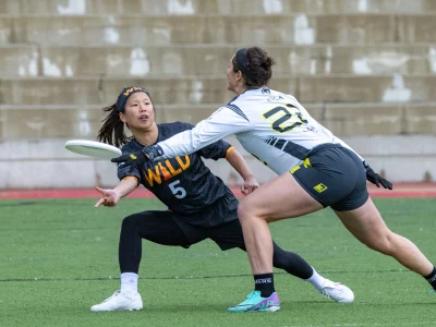 One women lunges to steal the frisbee out of another woman's hand.