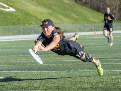 A girl leaps with a frisbee in her hand.