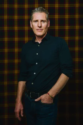 Peter Baxter poses in front of backdrop.