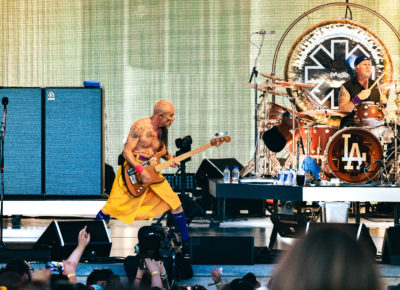 Flea stands with a wide stance playing bass in front of the fans, with Chad Smith playing drums to the side while on stage in Salt Lake City, Utah. Photo: @lmsorenson