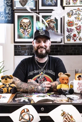 Tattoo artist Cory Harris sits at his desk.