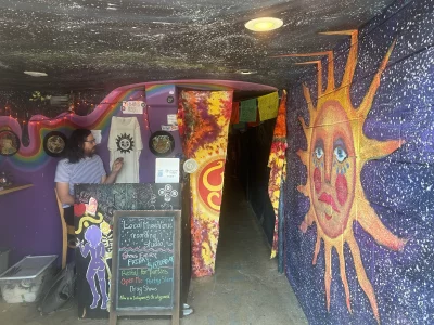 The whimsical entrance to WhySound. A sun with a face is painted atop a starry background on the wall next to the ticket booth.