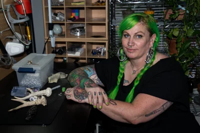 Kelly Green poses at their jewelry crafting station with some bones. 