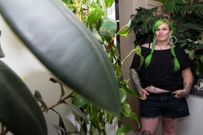 Kelly Green poses in a room of plants. 