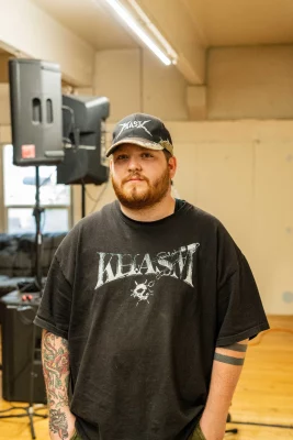 Julius Gray stands in the empty room of Black Lung Society in front of a PA. 