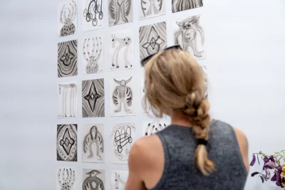 A woman views Russel Albert Daniels' drawings on a wall. 