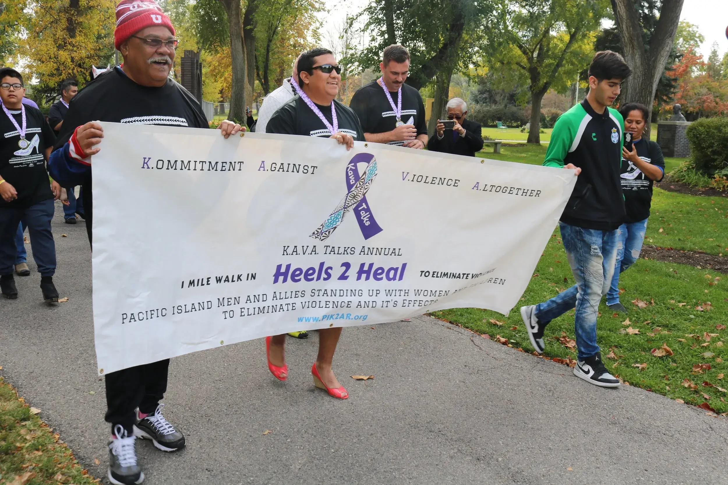 The members of KAVA Talks walking and holding a banner for the In Heels 2 Heal event.