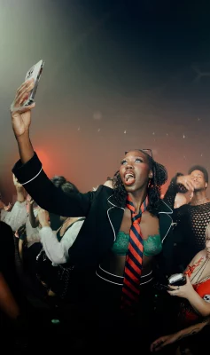 Women in concert crowd holds up her phone to take a picture.