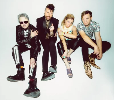 The band Neon Trees sit in various poses in a white room. 