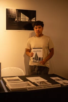 Miguel Hernandez holding up his art book, Unveiled. 