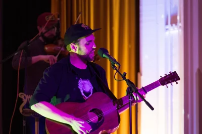 Sean Baker performs vocals and guitar with a backup violinist. 