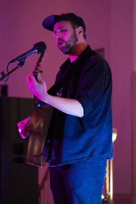 Sean Baker sings and plays guitar on stage at an open mic at The Clubhouse. 