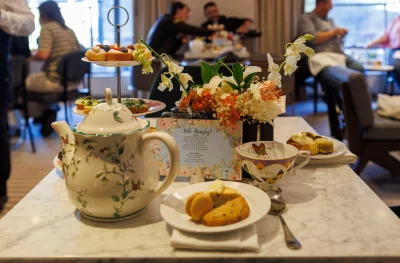 An elegant tea pot and treats sit on a marble table. 