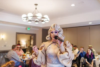 Scarlett Kiss gives a speech in a cream outfit with a retro-styled blonde wig. 