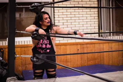 Princess Deathwish stands in the corner of the ring in torn clothes and smudged lipstick. 