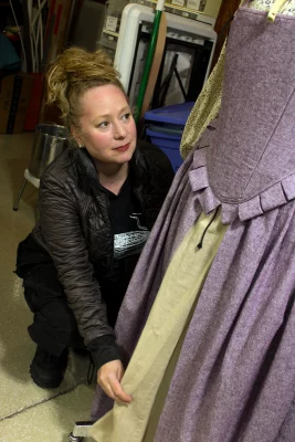 Jennifer McGrew adjusts the hem of a purple and cream dress. 